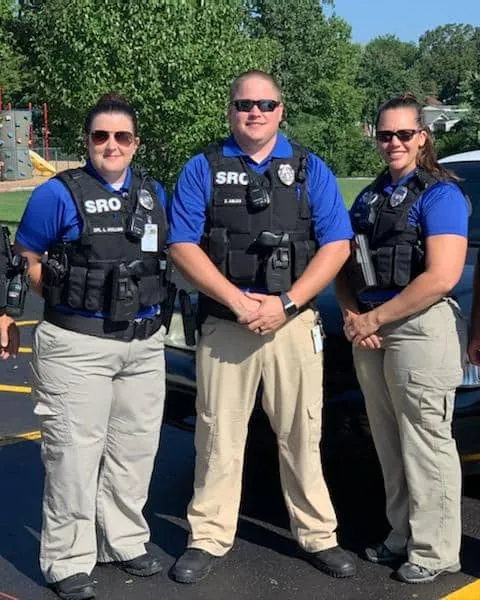 Three school resource officers in blue uniforms wearing Cowell external carriers
